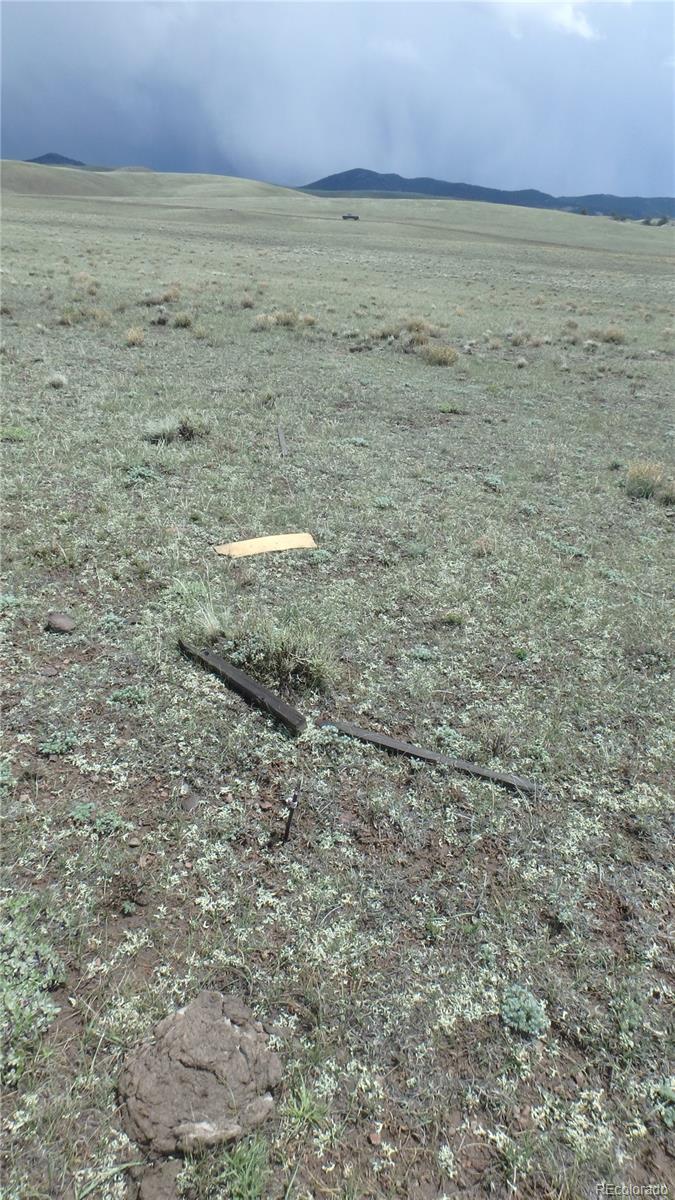 Vacant grassland with rolling hills, distant mountain ridges, and scattered debris in the foreground.