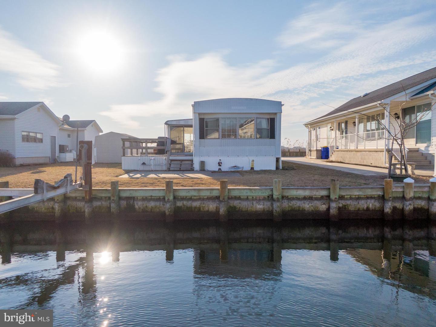 Waterfront home across a canal, with a small rear deck and neighboring houses.