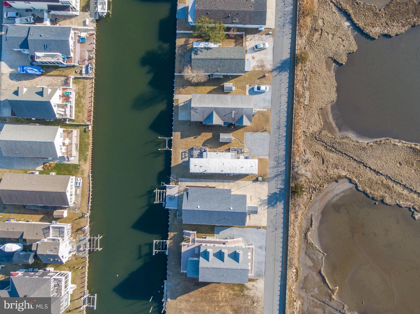 Aerial view of canal-side homes with docks beside a broad marsh.