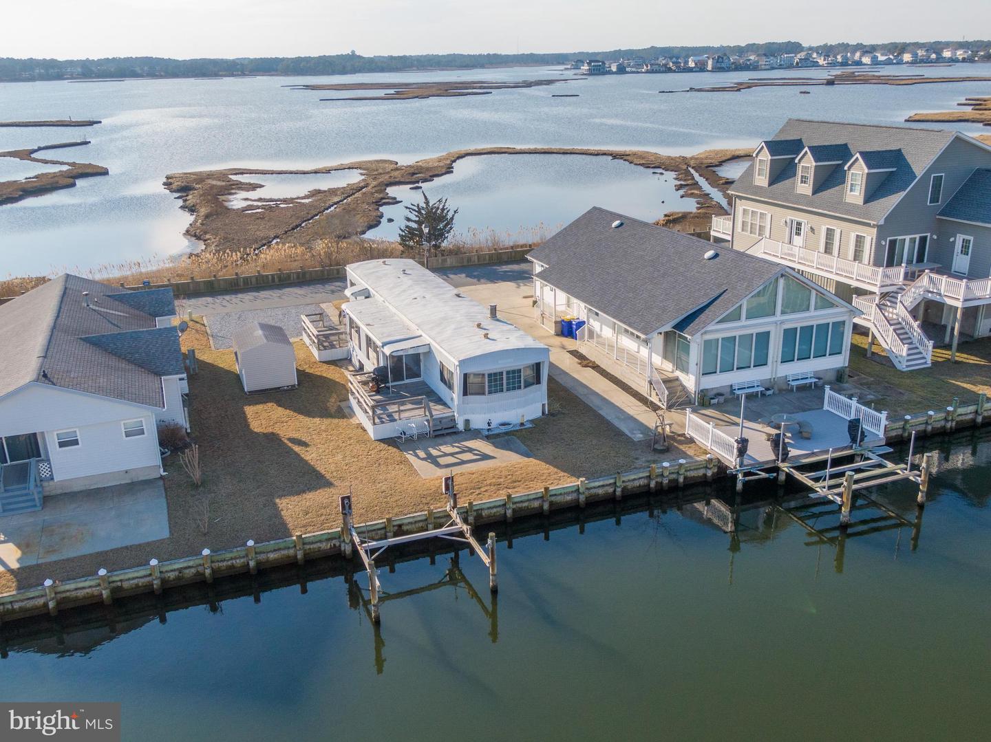 Aerial view of waterfront homes and docks beside a broad marsh estuary.