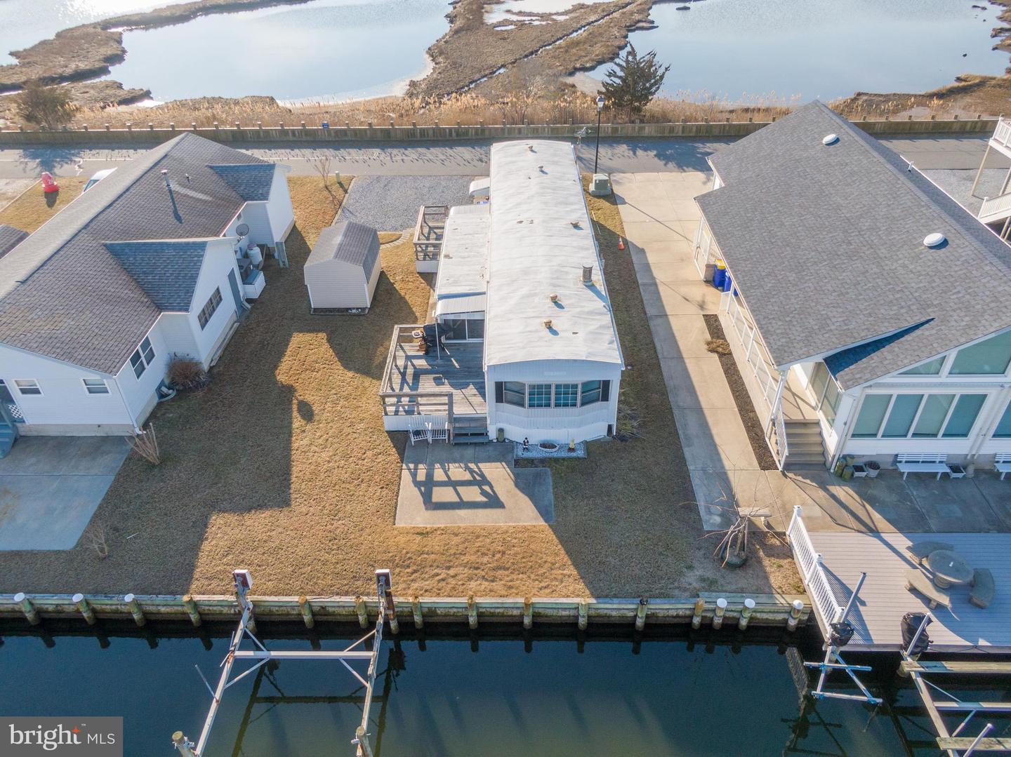 Waterfront manufactured home with a deck, canal, and dock slips in front.