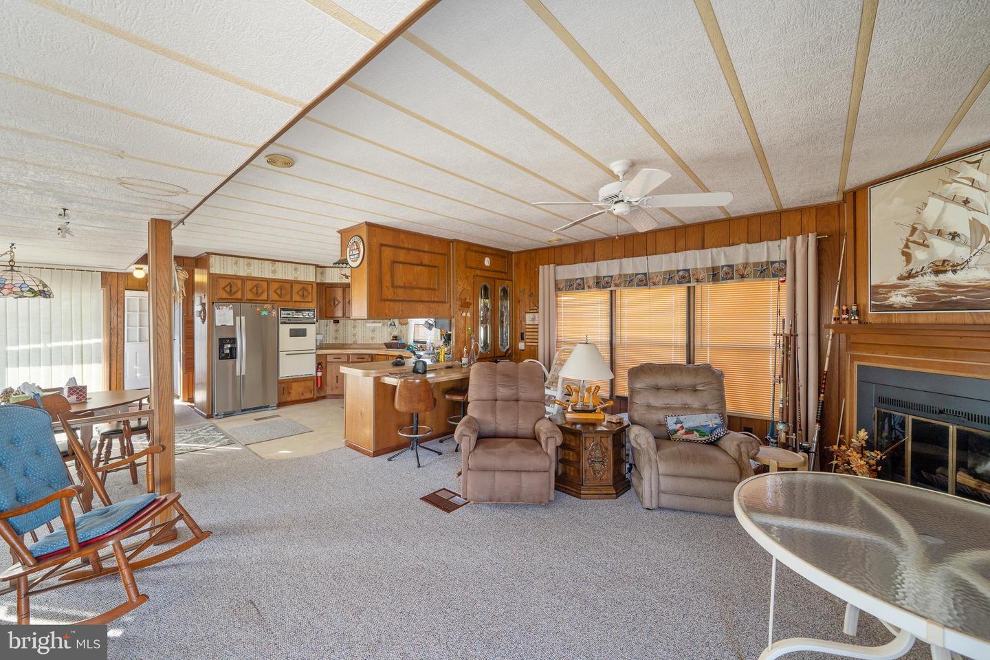 Living room with wood-paneled walls, recliners, fireplace, and an open kitchen.