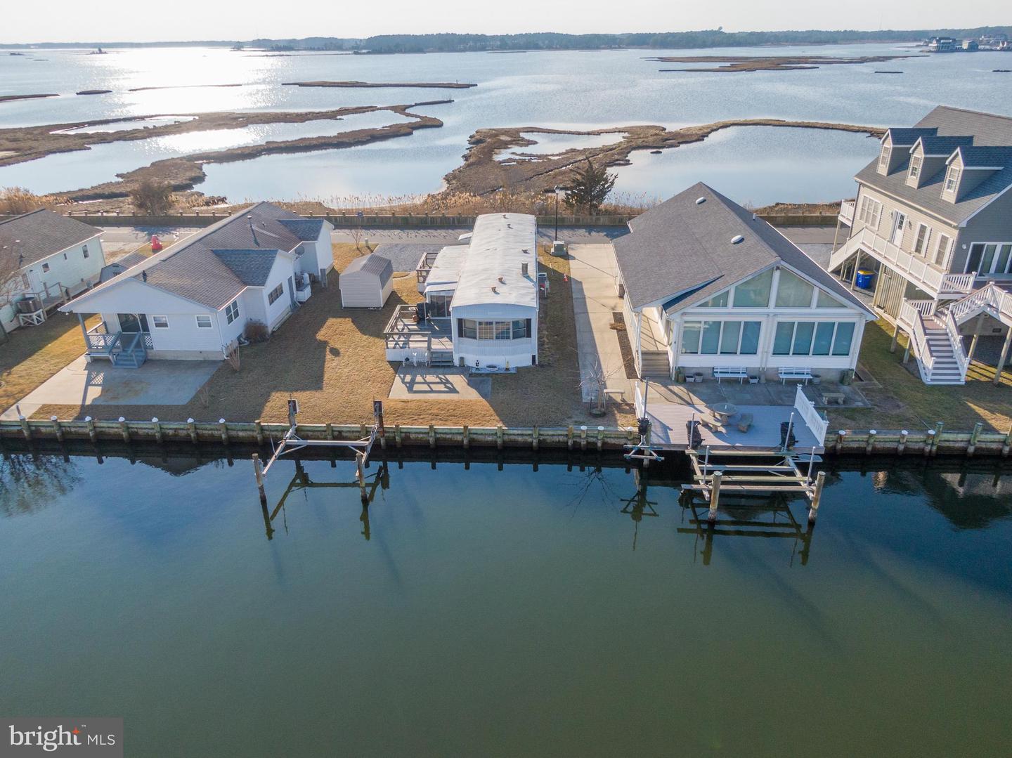 Aerial view of waterfront homes, docks, marsh islands, and open bay.