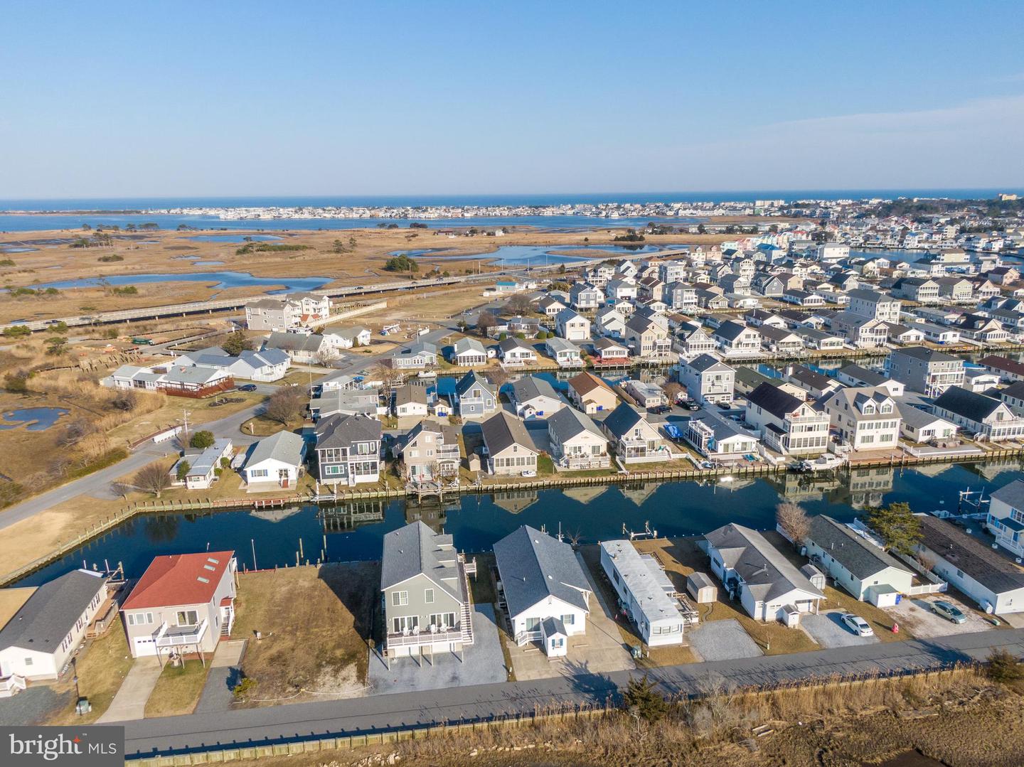 Aerial view of coastal homes lining canals, with marshland and ocean beyond.