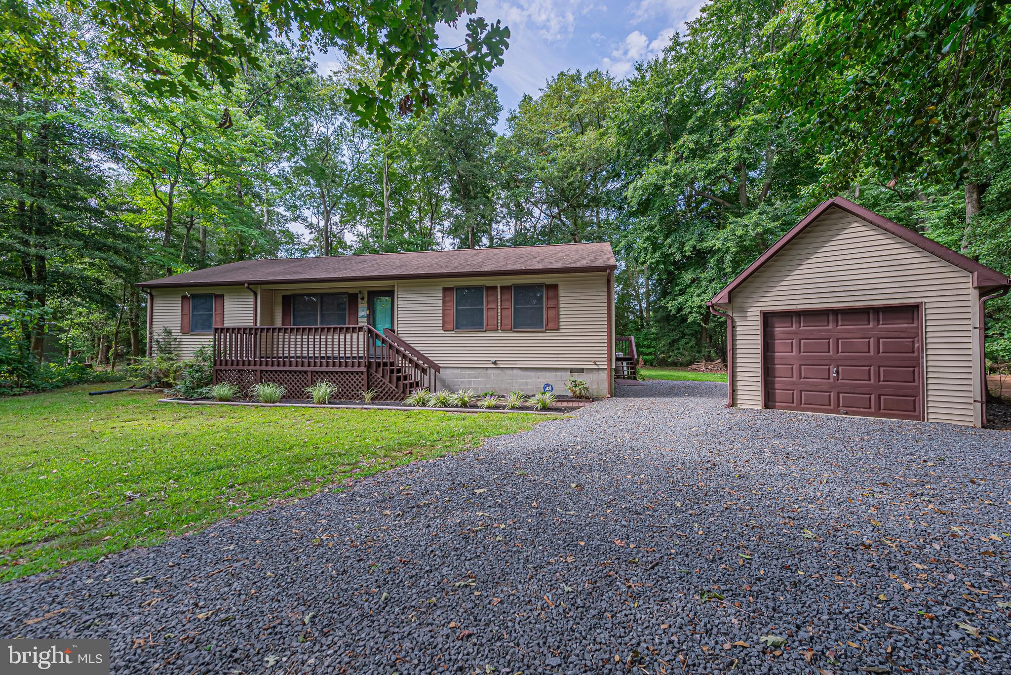 Single-story home with a covered porch and detached garage on a wooded lot.