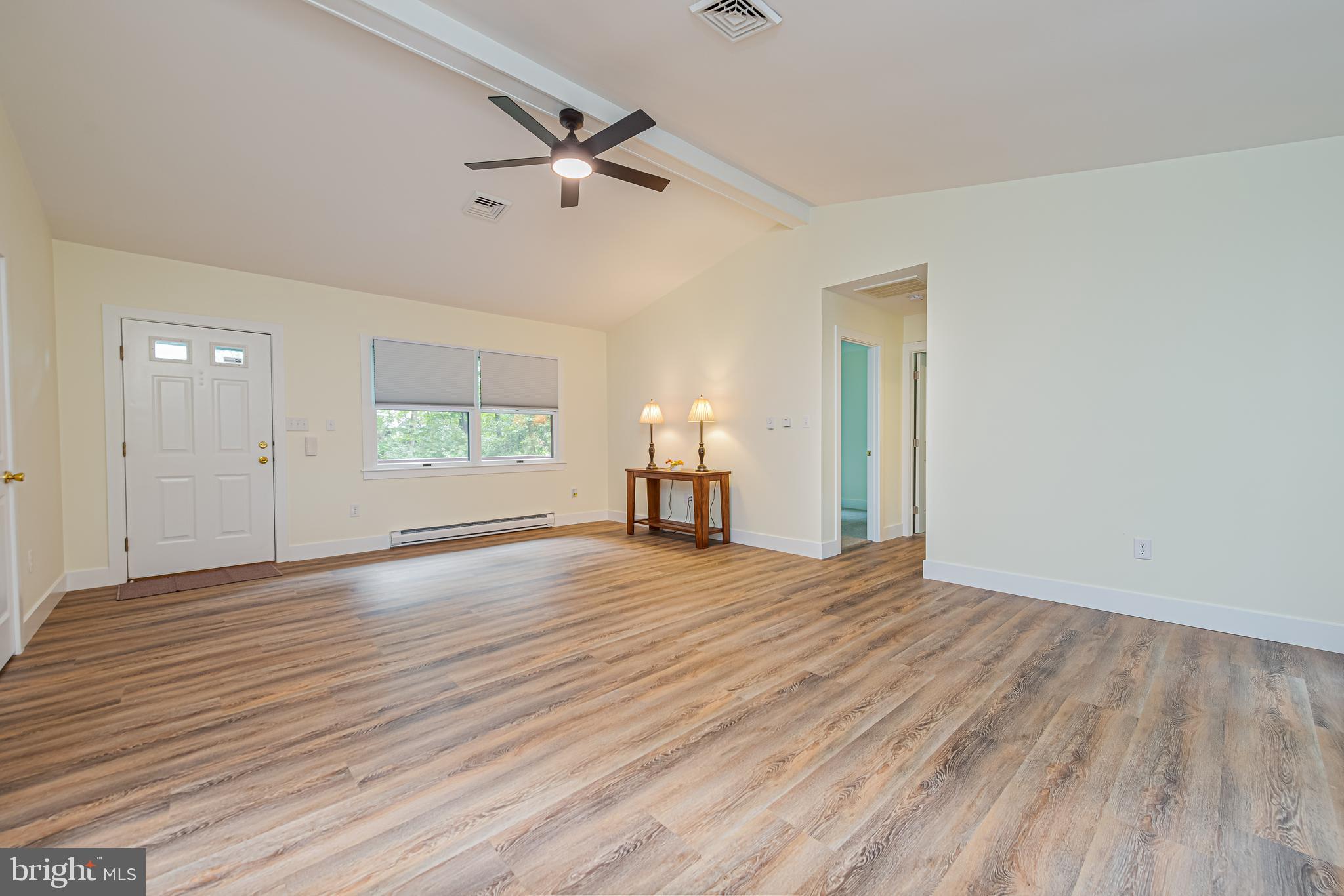 Living room with wood-look flooring, a ceiling fan, and a small table with two lamps.