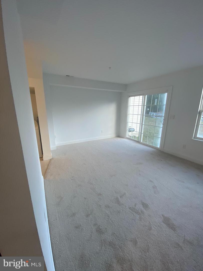 Empty carpeted living room with sliding glass doors opening to a backyard.