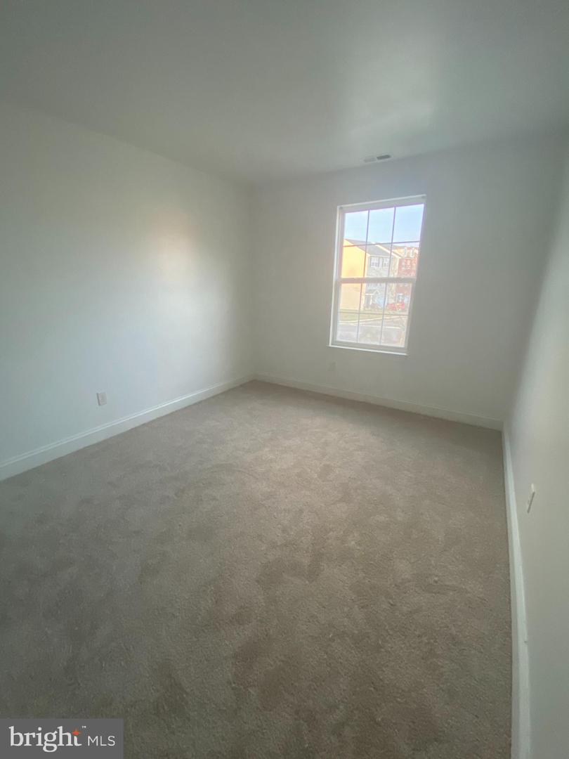 Empty bedroom with beige carpet and a single window.