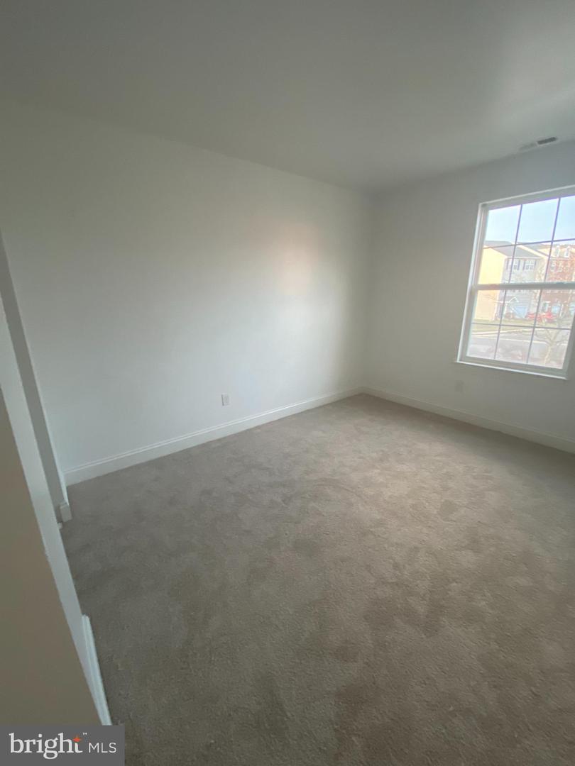 Unfurnished carpeted room with white walls and a large multi-pane window.