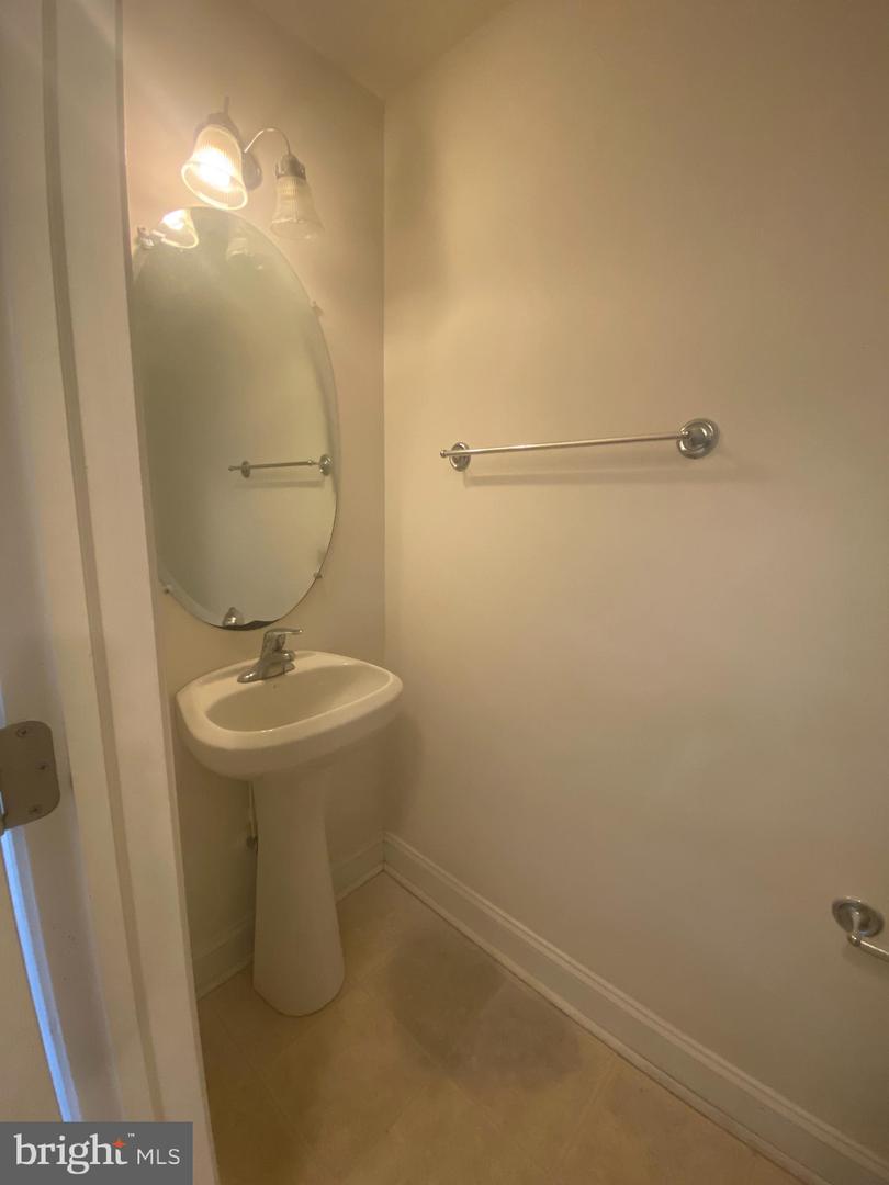 Small bathroom with a pedestal sink, oval mirror, and chrome towel bar.