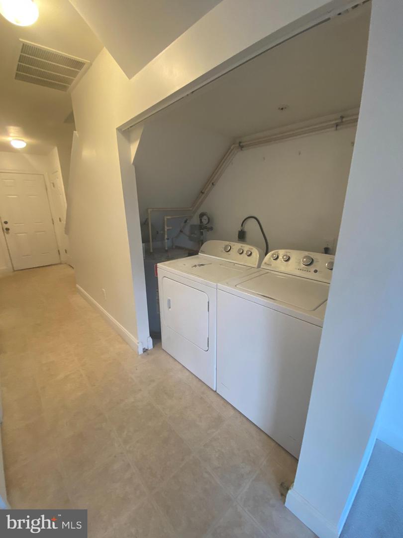 Laundry area with a white washer and dryer in an open alcove beside a hallway.