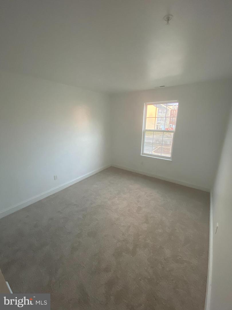 Empty bedroom with beige carpet and a single window.