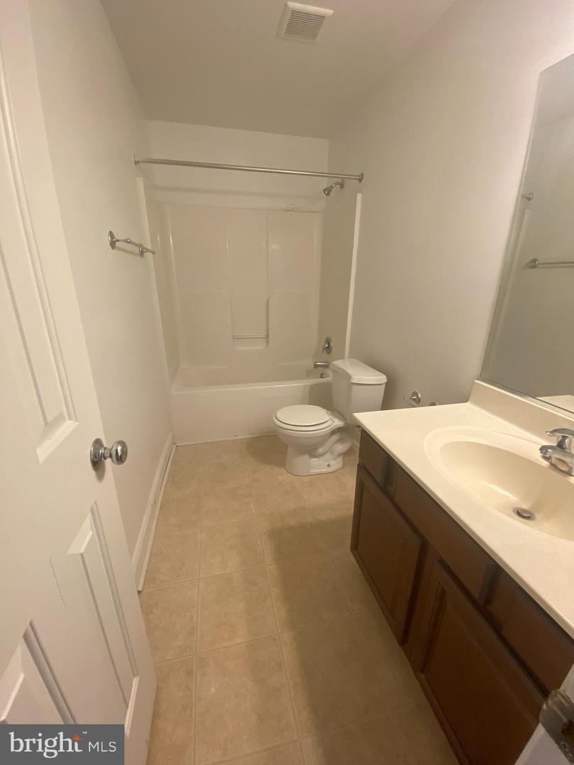 Bathroom with a tub-shower, toilet, and dark wood vanity with a large mirror.