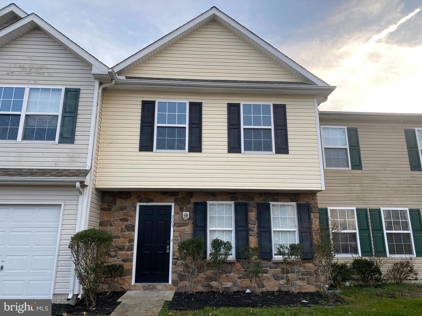 Two-story attached home with a stone-front entrance, dark shutters, and an attached garage.
