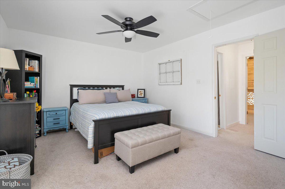 Bedroom with a dark wood bed, striped bedding, blue nightstands, and a ceiling fan.