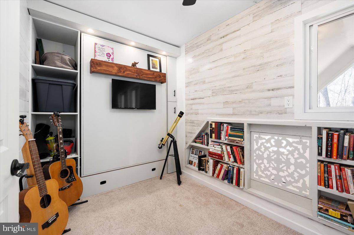 Den with a closed Murphy bed, guitars, telescope, and built-in bookshelves.