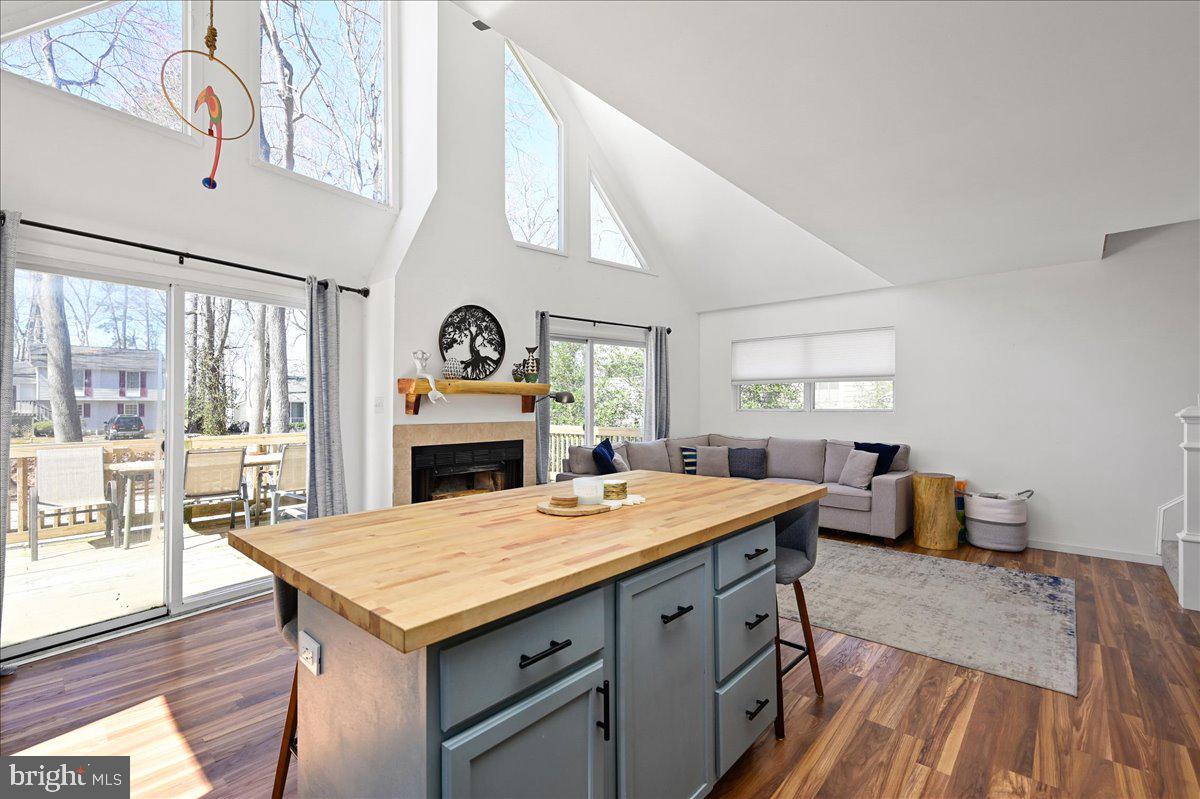 Open-plan kitchen and living room with a large wood-topped island, fireplace, and vaulted ceiling.