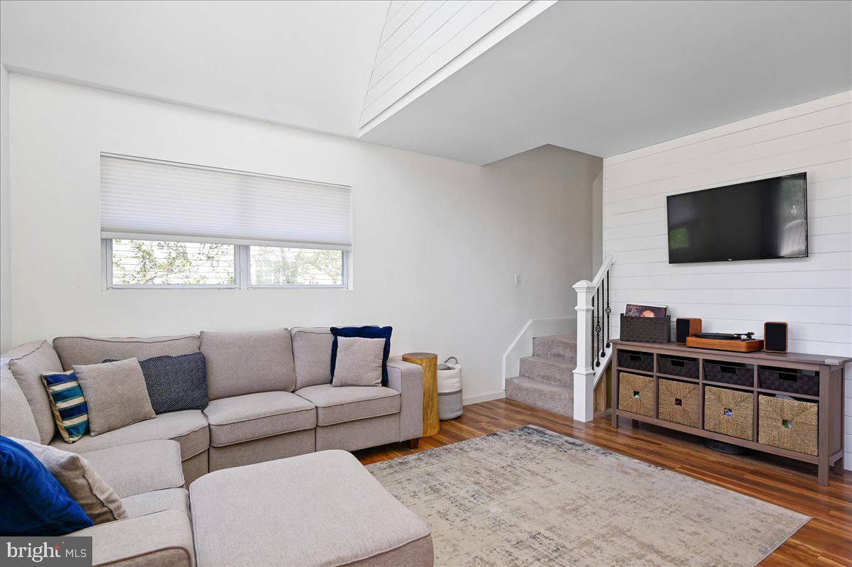 Furnished living room with a sectional sofa, wood floors, and a television above a media console.
