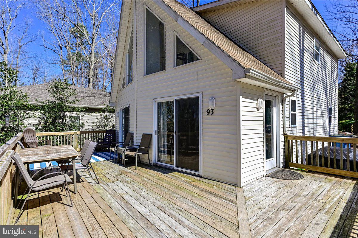 House exterior with a spacious wooden deck, sliding glass doors, and patio furniture.
