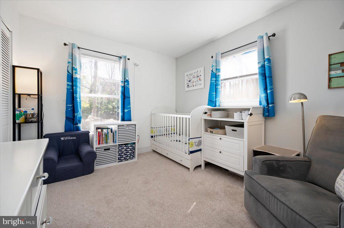 Nursery with a white crib, changing dresser, and blue curtains between two windows.