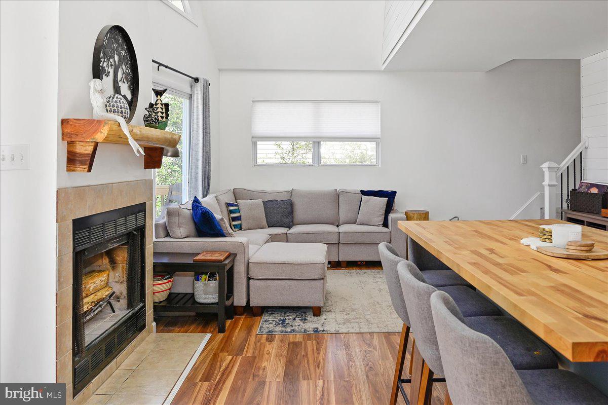 Living room with a stone fireplace, gray sectional, wood floors, and adjoining dining table.