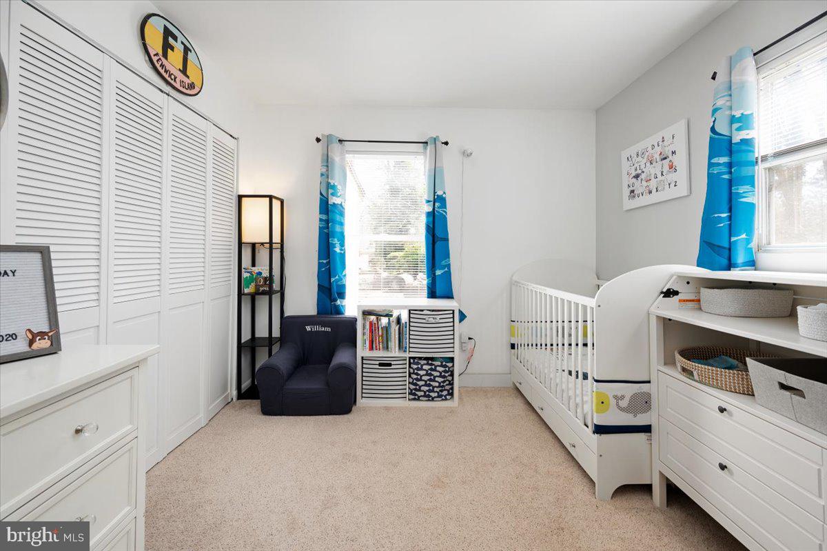 Nursery with a white crib, louvered closet doors, and blue ocean-pattern curtains.