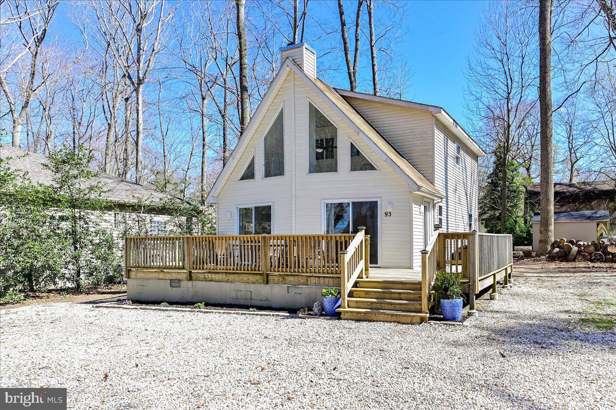 White two-story home with triangular gable windows and a raised wooden front deck.
