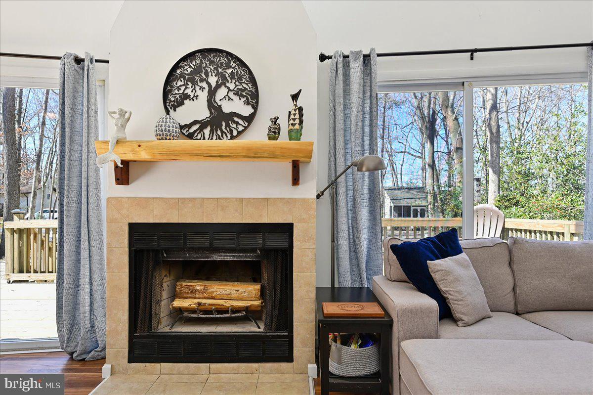 Living room with a tiled fireplace, gray sectional, and large windows overlooking a deck.