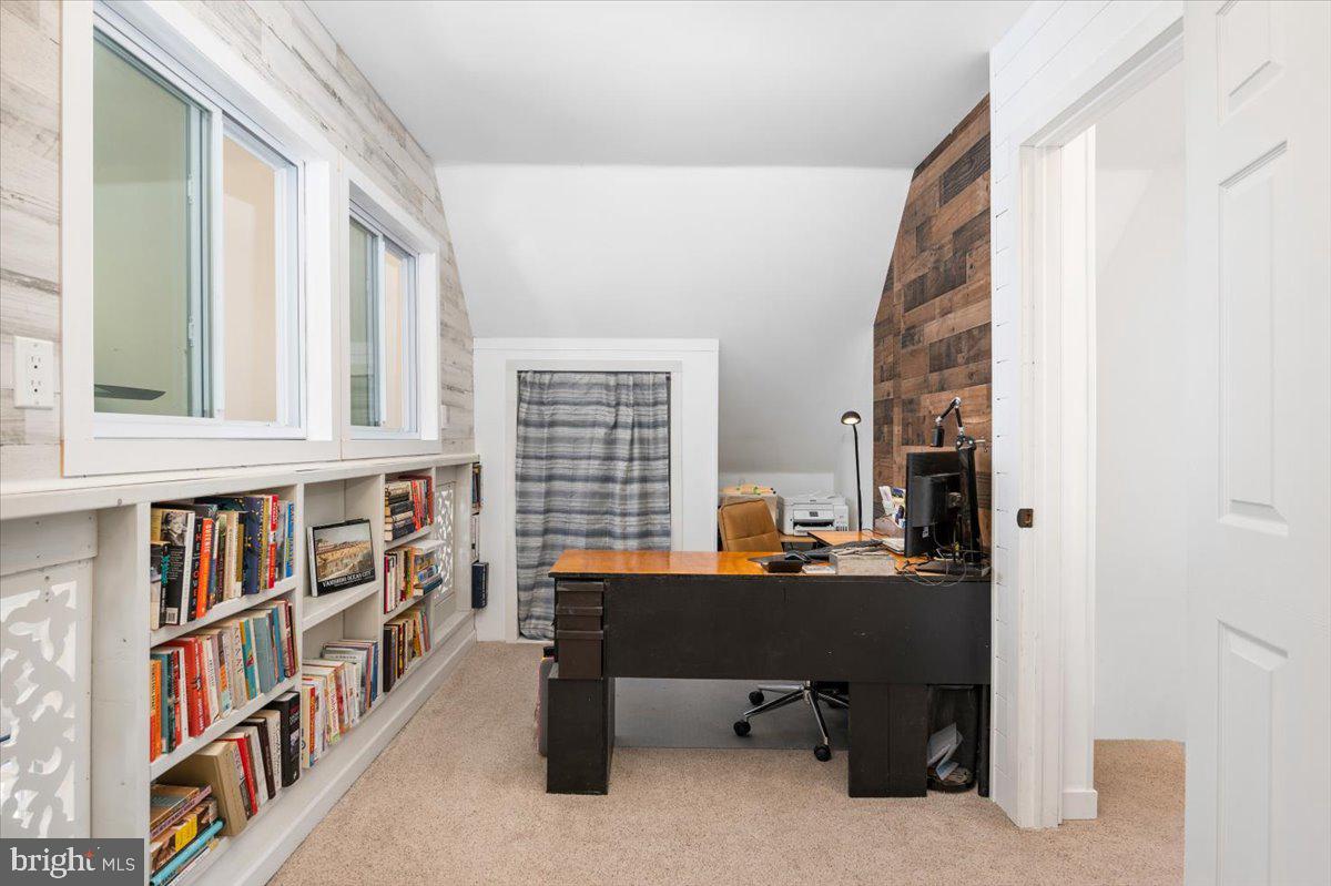 Home office with built-in bookshelves, a dark desk, and a wood accent wall.