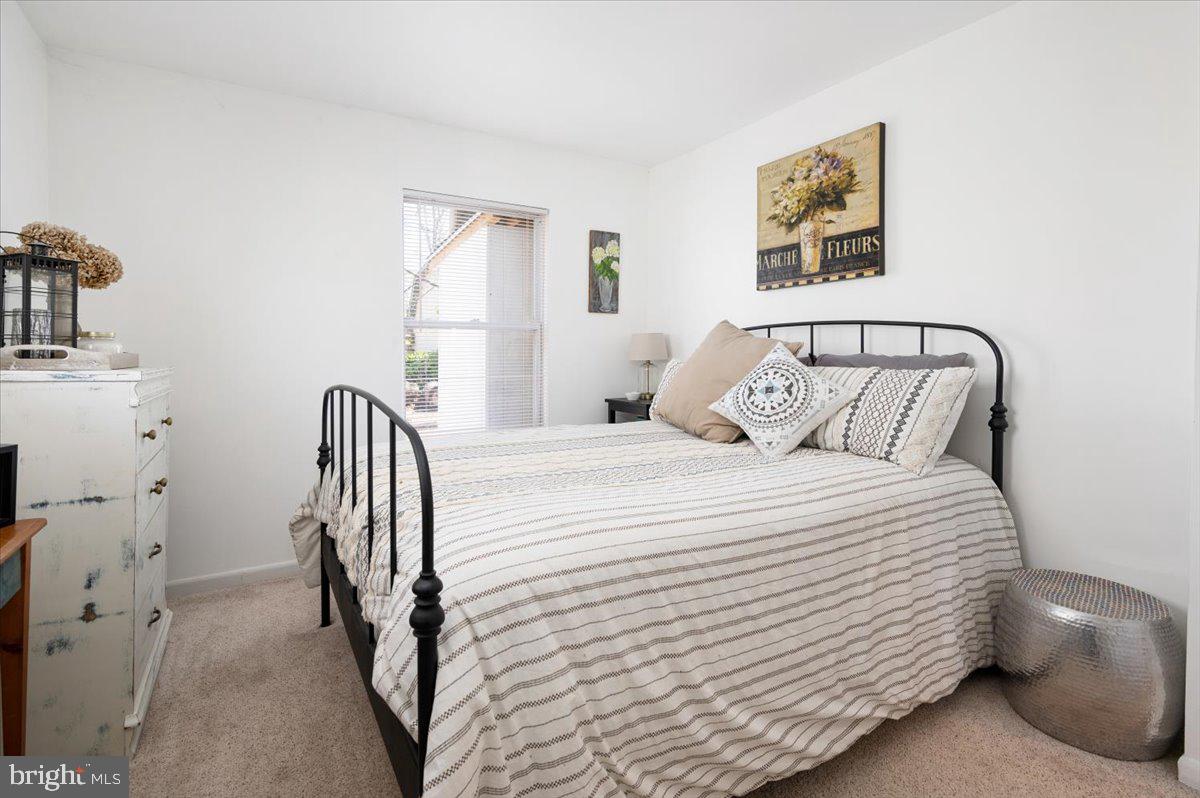 Bedroom with a black metal bed, striped bedding, and a window with blinds.
