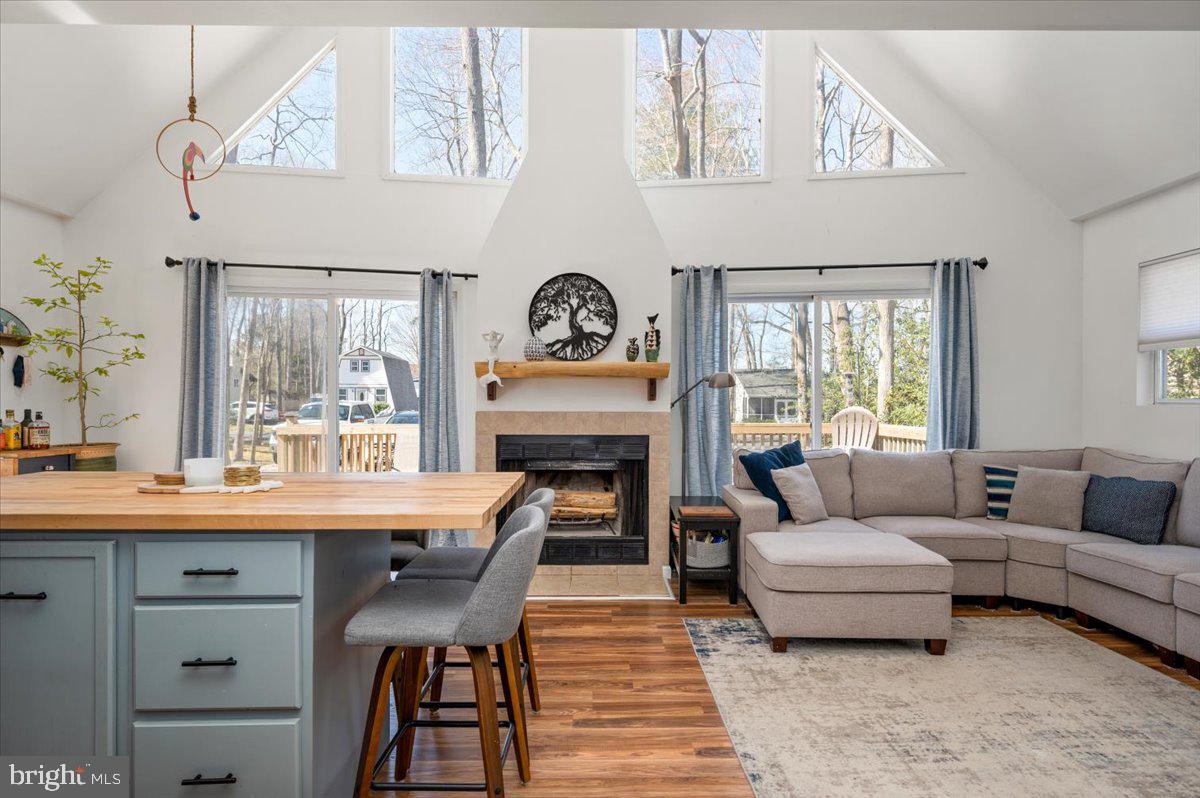 Open-plan living room with a fireplace, vaulted ceiling, gray sectional, and blue-gray kitchen island.