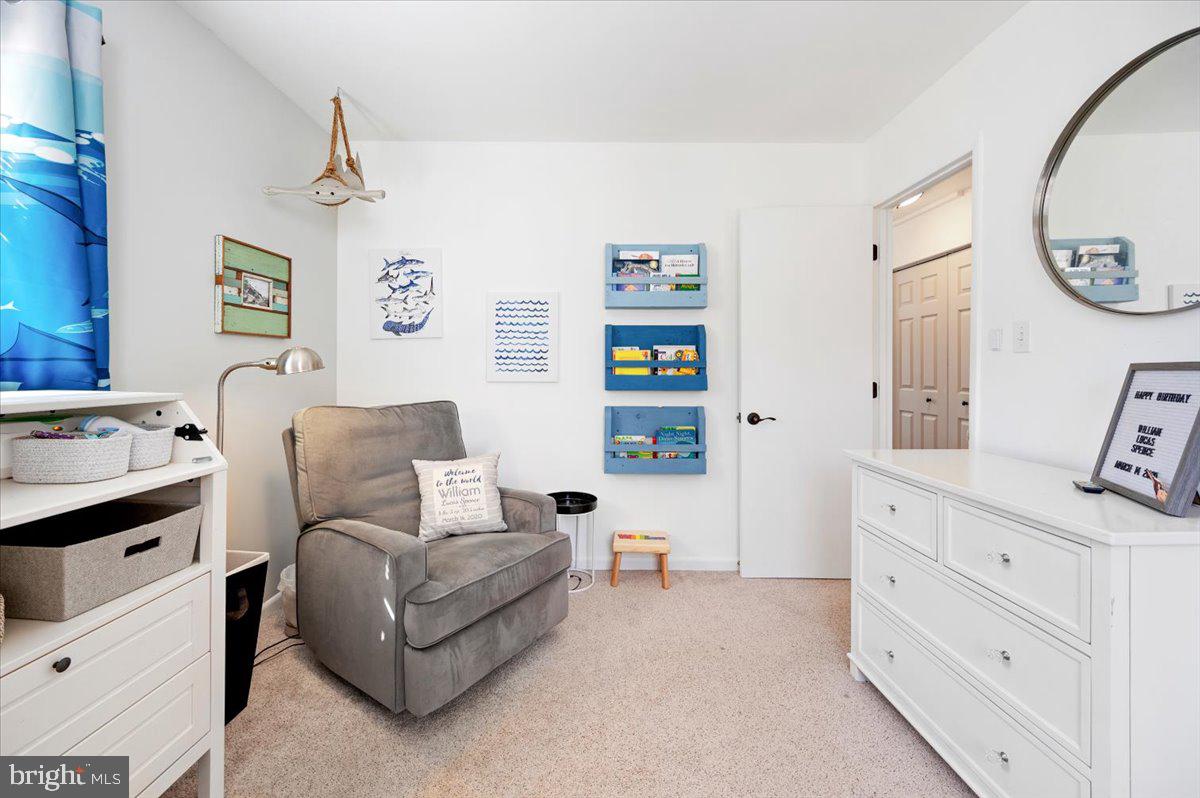 Furnished nursery with a gray glider, children's book racks, and blue nautical decor.