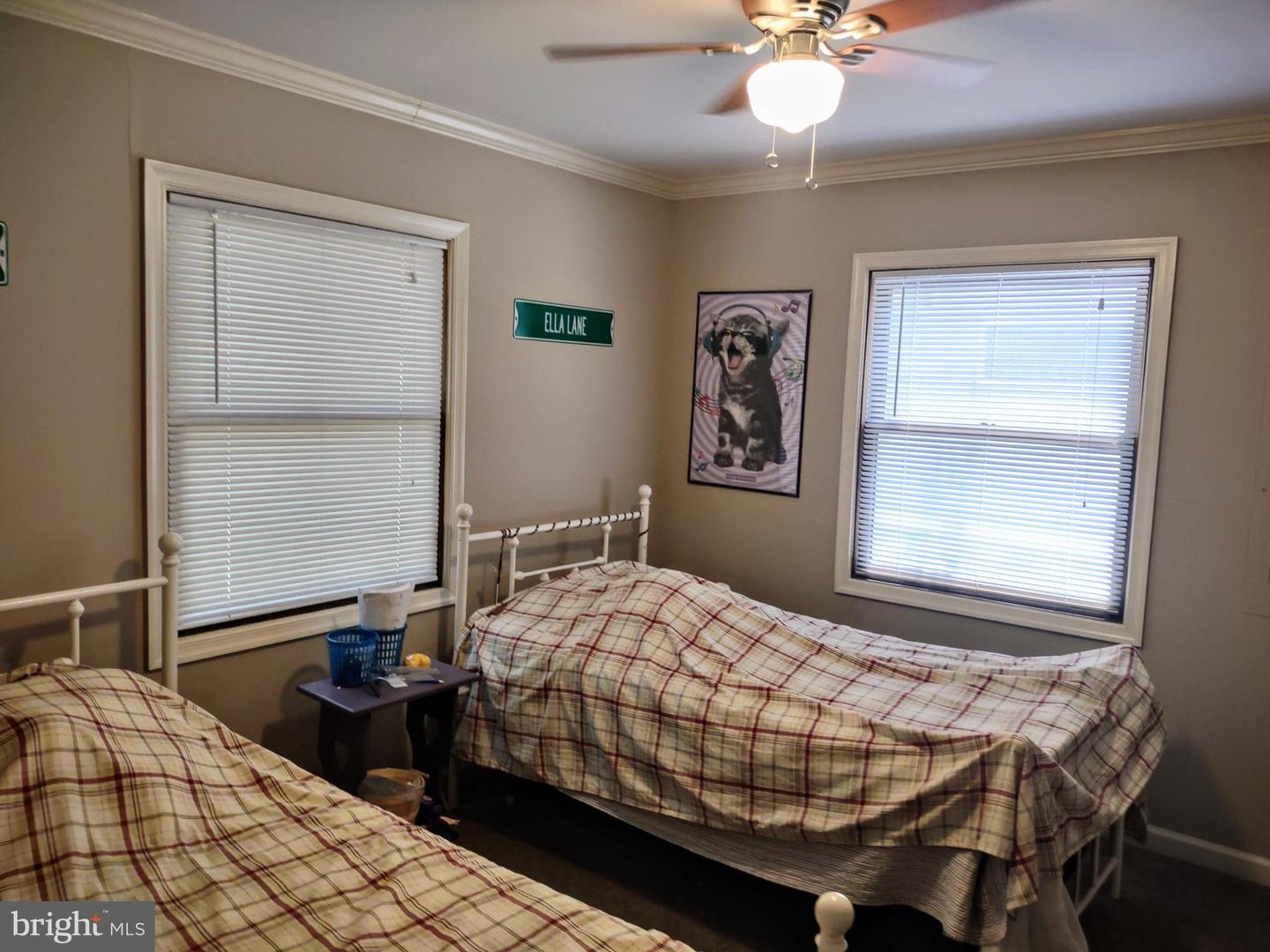 Bedroom with two plaid-covered beds, window blinds, and a ceiling fan.
