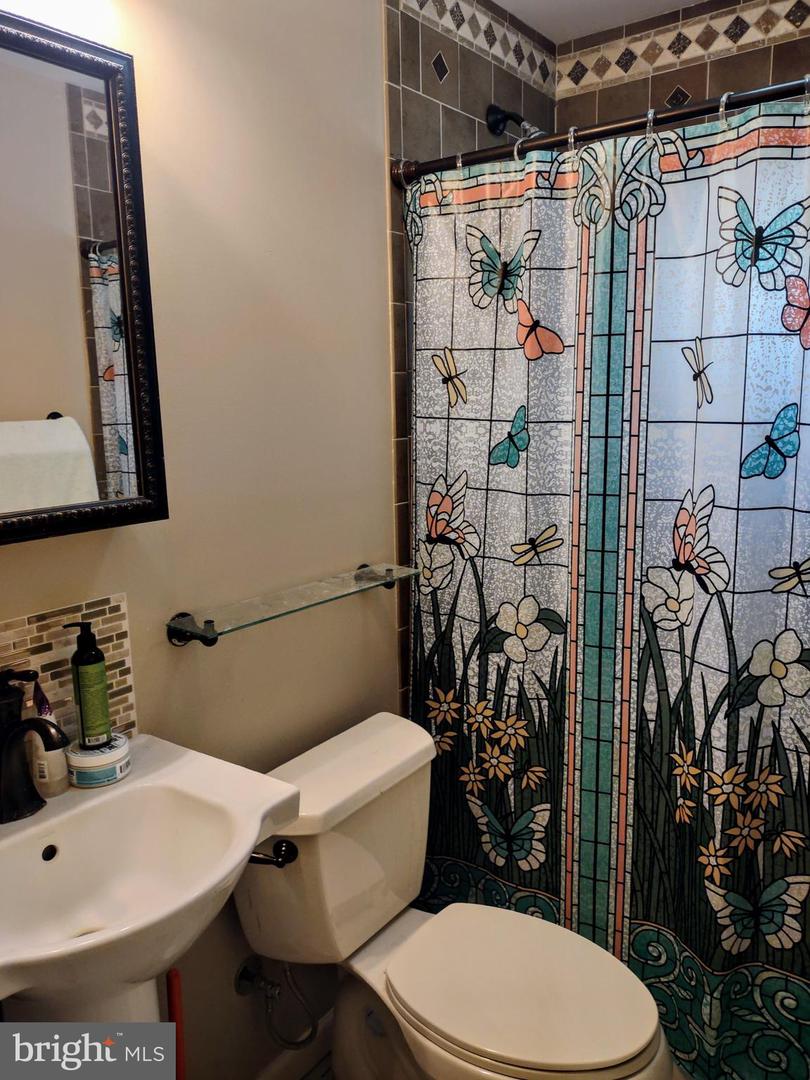 Bathroom with a floral butterfly shower curtain beside a white sink and toilet.