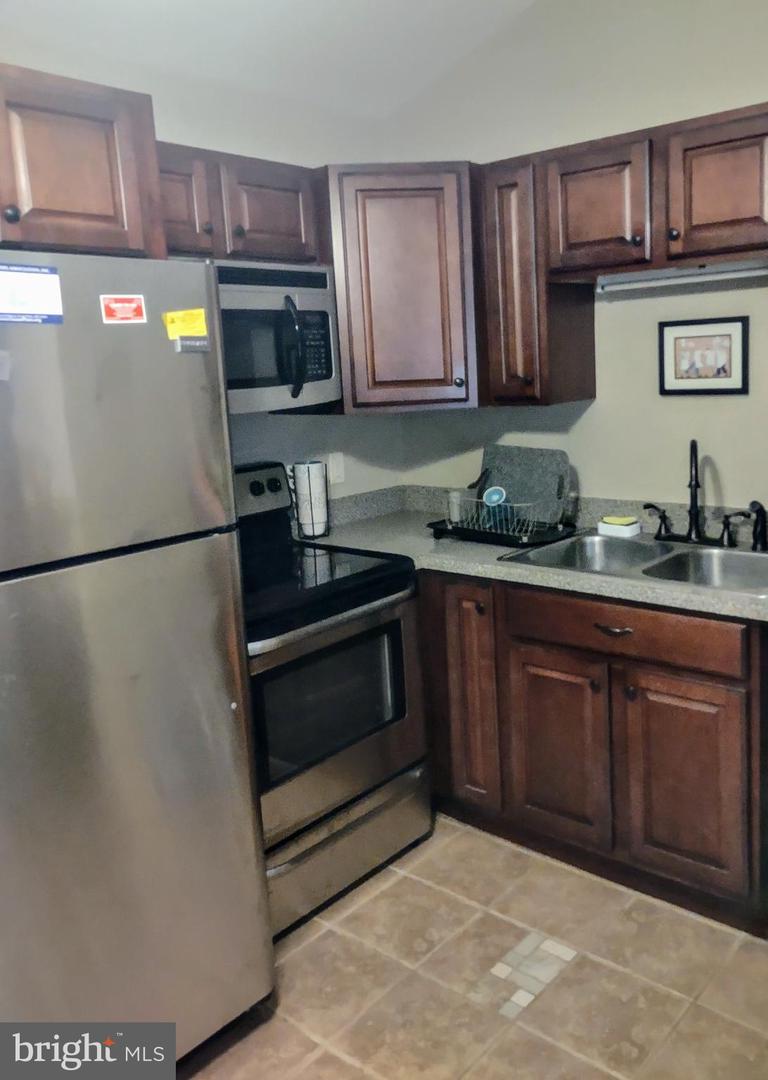Kitchen with dark wood cabinets, stainless steel appliances, and a double-basin sink.