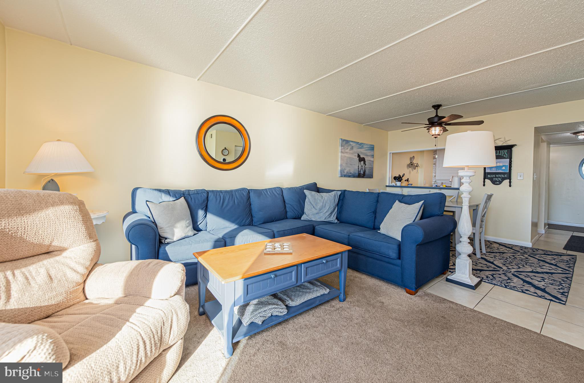 Living room with a blue sectional sofa, cream recliner, and blue-and-wood coffee table.
