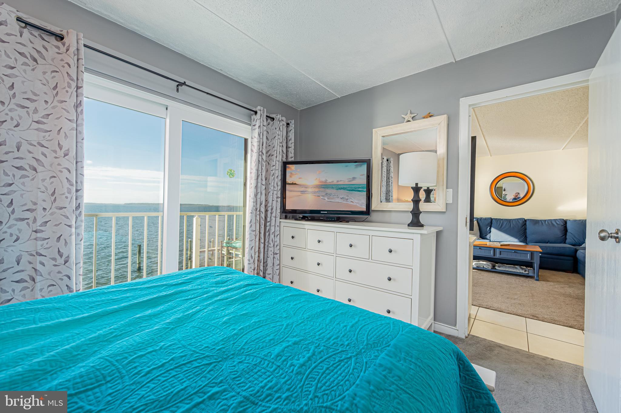 Bedroom with a turquoise bedspread and sliding doors overlooking the ocean.