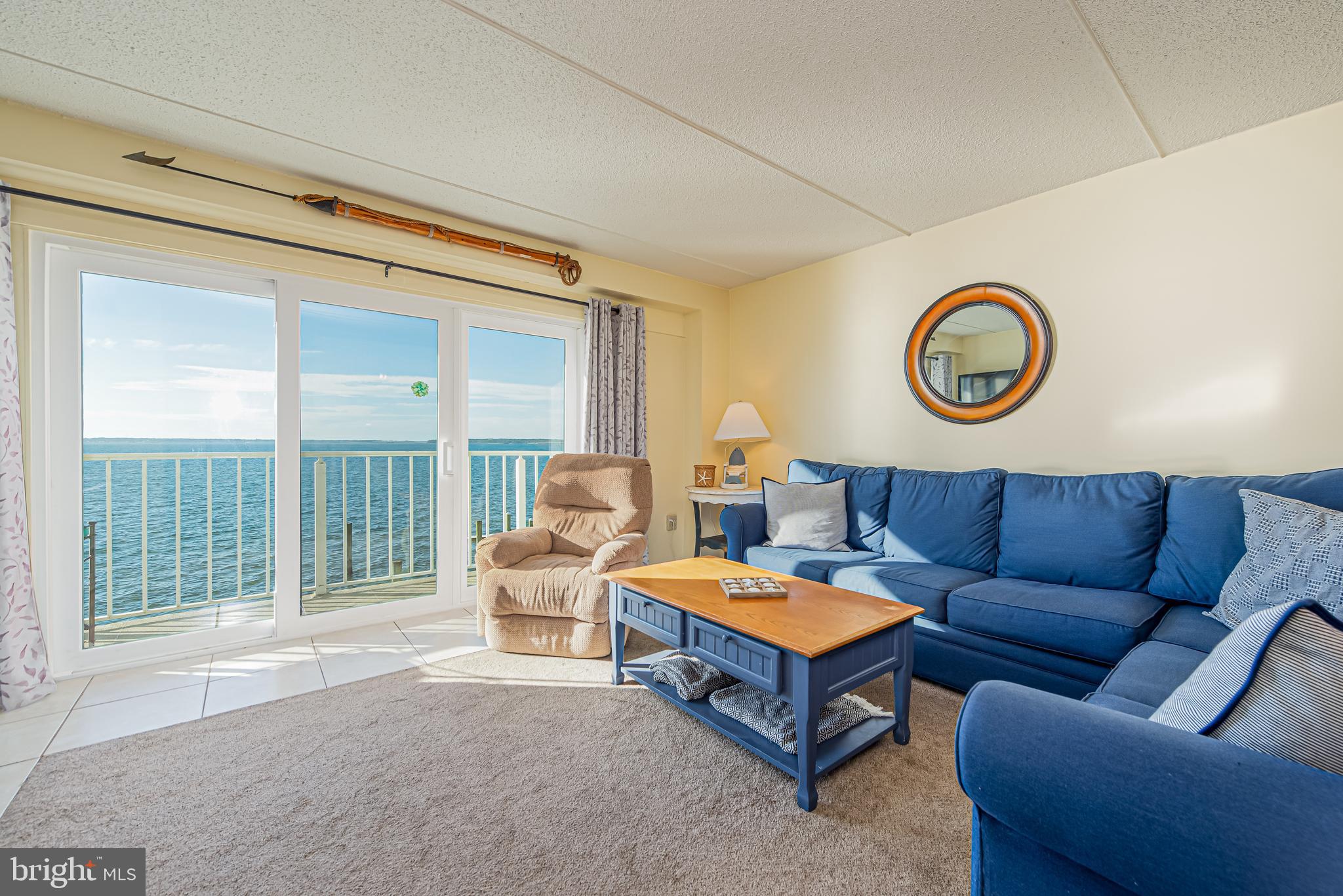 Living room with blue sectional and balcony doors overlooking the water.