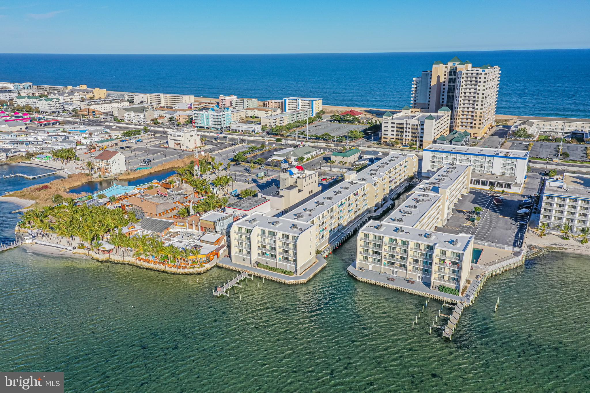 Aerial view of waterfront condominiums and docks, with Ocean City beach and ocean beyond.
