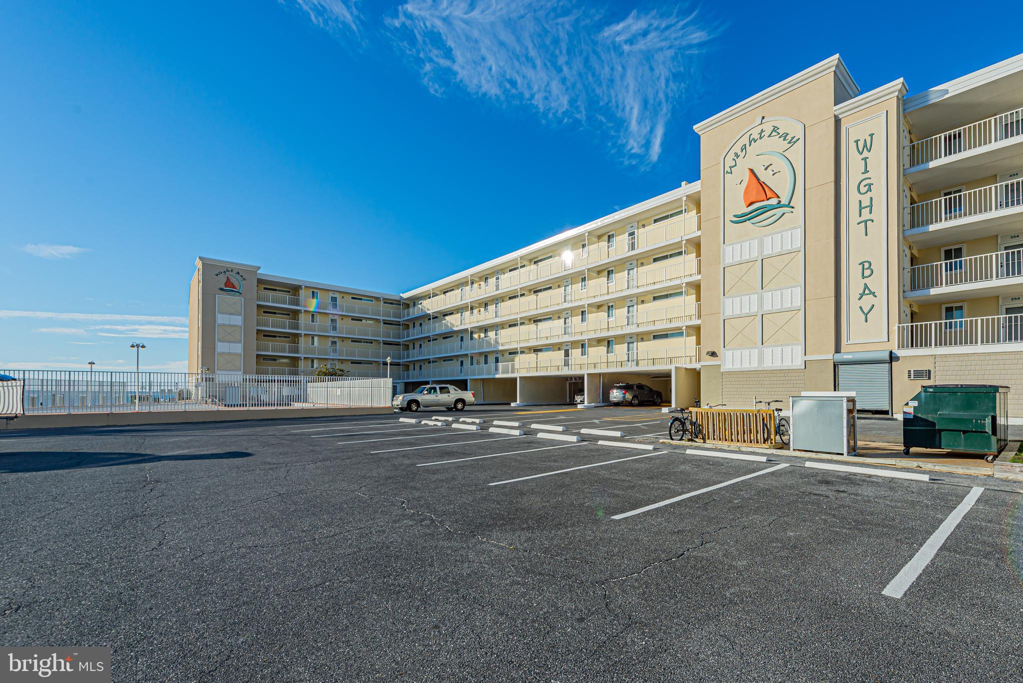 Wight Bay condominium exterior with multistory balconies and a large parking lot.