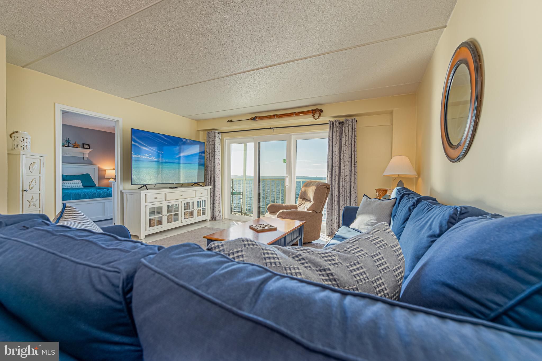 Living room with a blue sectional and sliding doors overlooking the water.