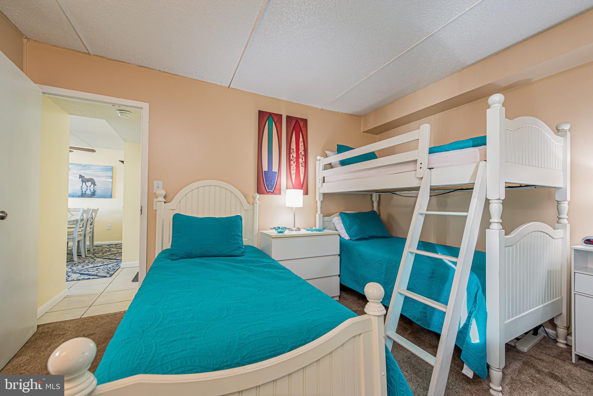 Bedroom with teal bedding, a white twin bed, and a matching bunk bed with ladder.