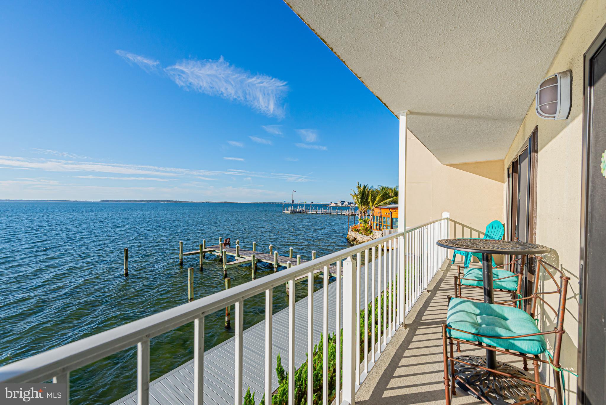 Waterfront balcony with turquoise seating overlooking the bay and private docks.