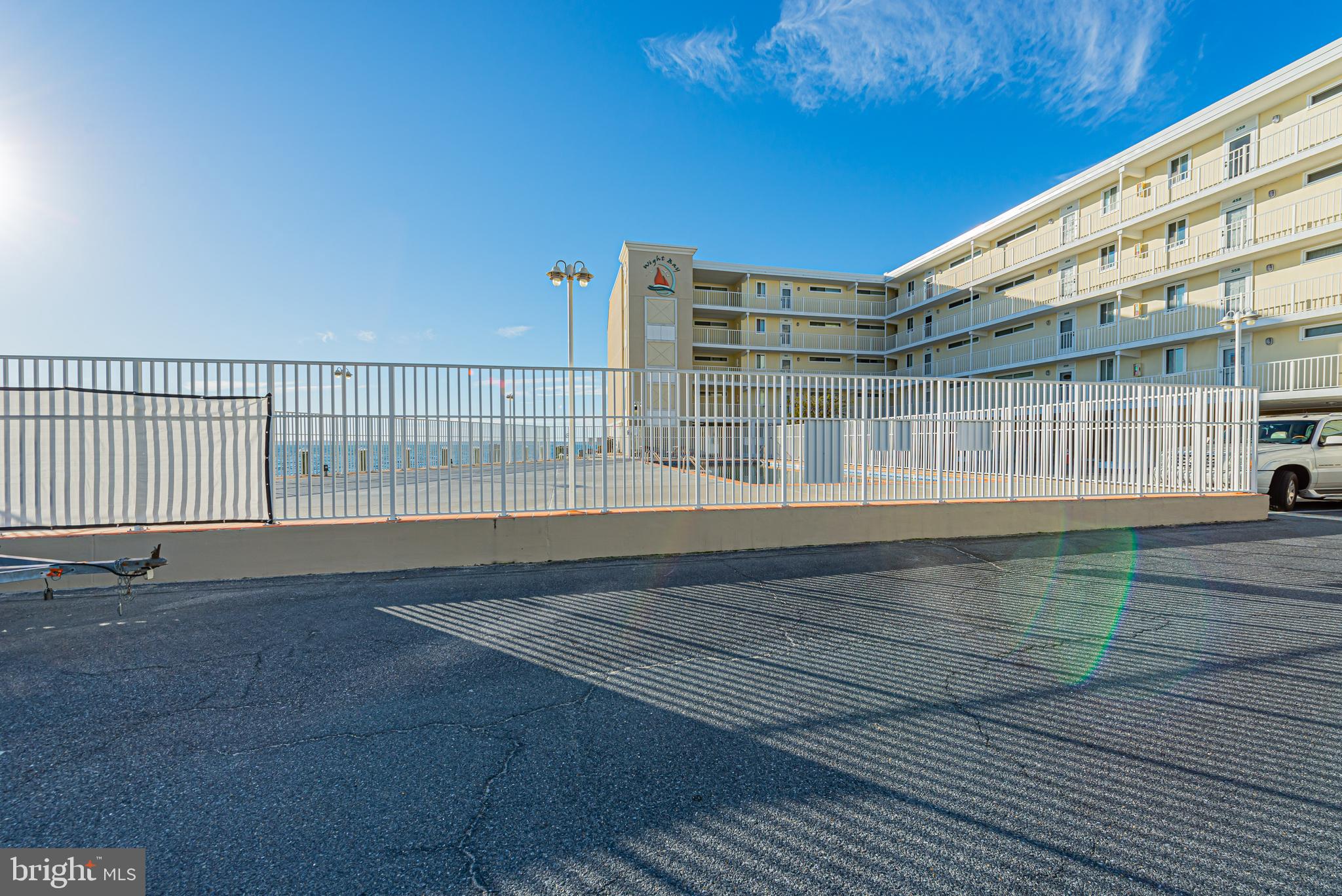 Beachfront condominium with a fenced pool area and ocean visible beyond.