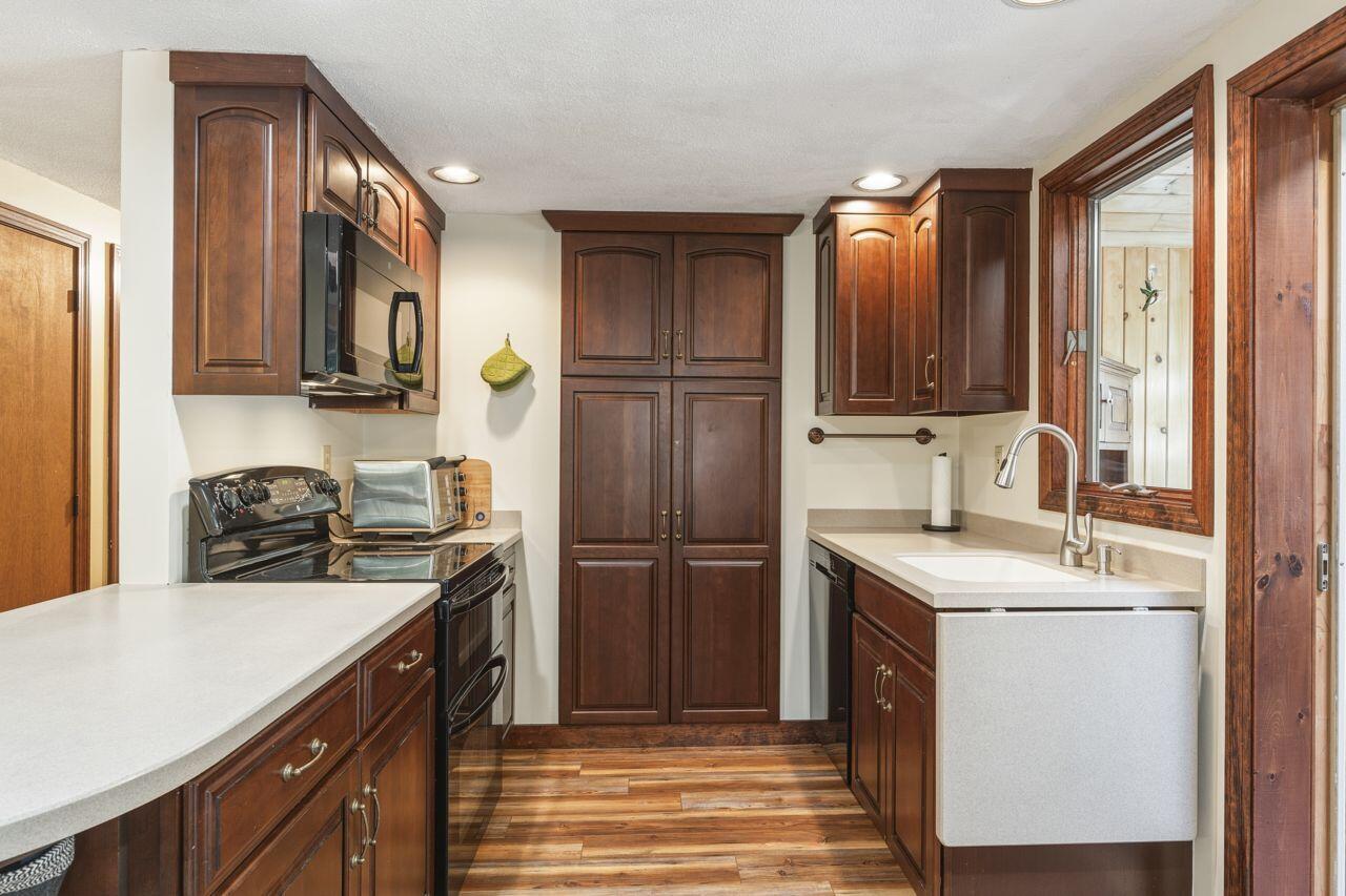 Kitchen with dark wood cabinets, white countertops, and a farmhouse-style sink.