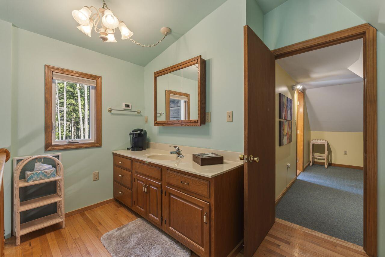 Bathroom with a wood vanity, mirrored cabinet, and window overlooking trees.