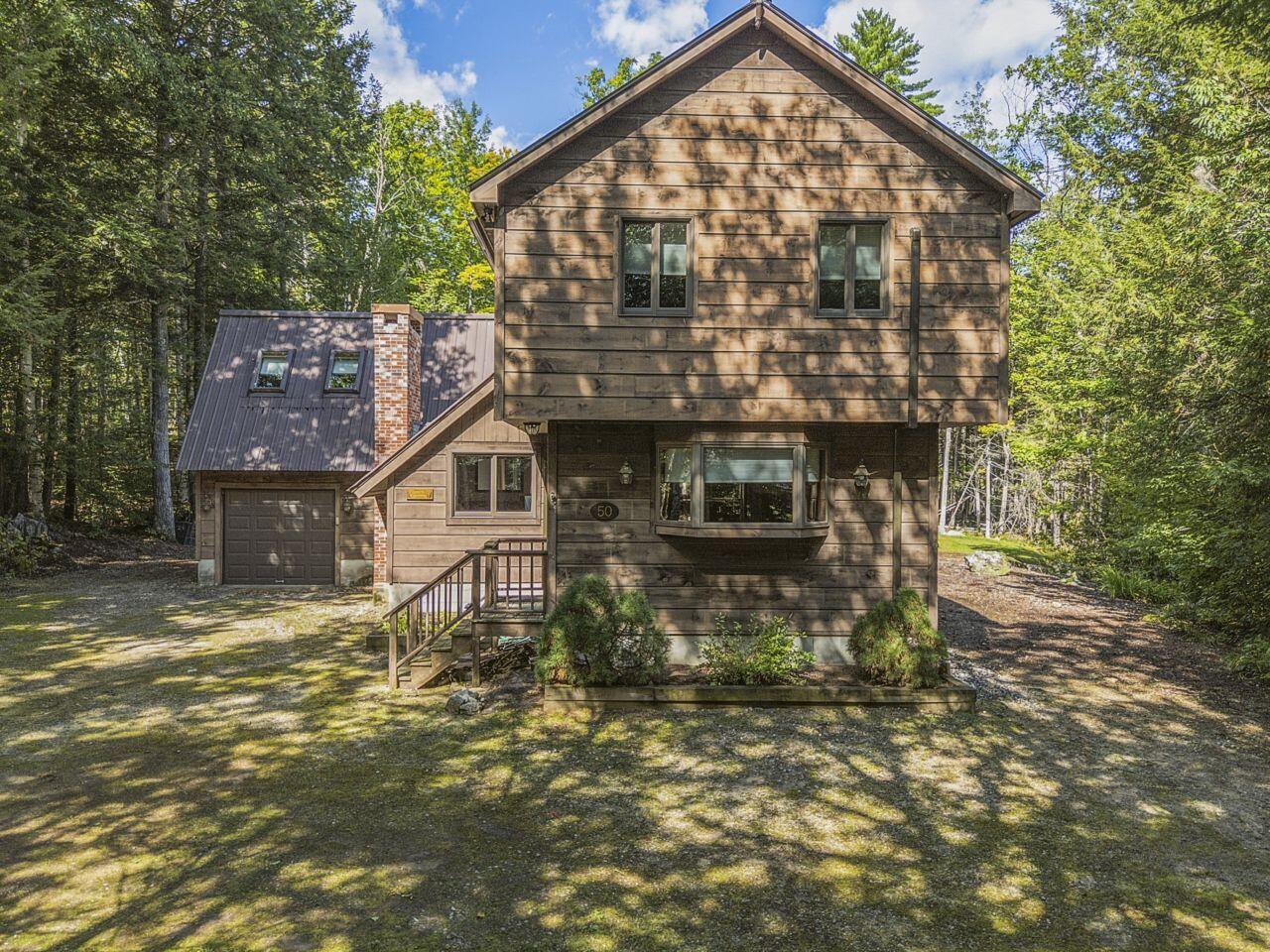 Wood-sided two-story home with an attached garage, surrounded by trees.