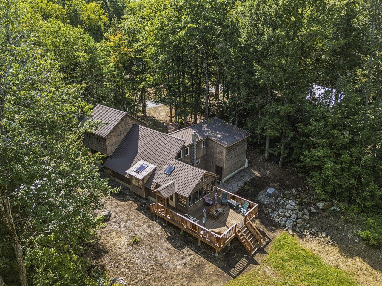 Wood-sided home nestled among trees, with a large deck and rocky landscaping.