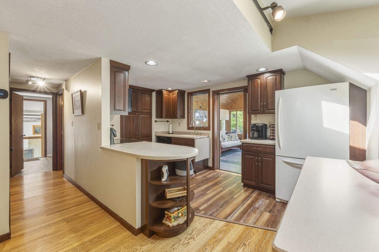 Kitchen with dark wood cabinets, a curved peninsula, white refrigerator, and hardwood floors.