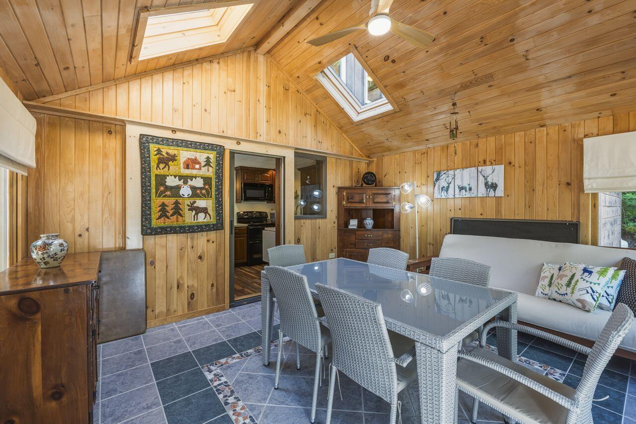 Wood-paneled dining and sitting room with a glass-top table and skylights.